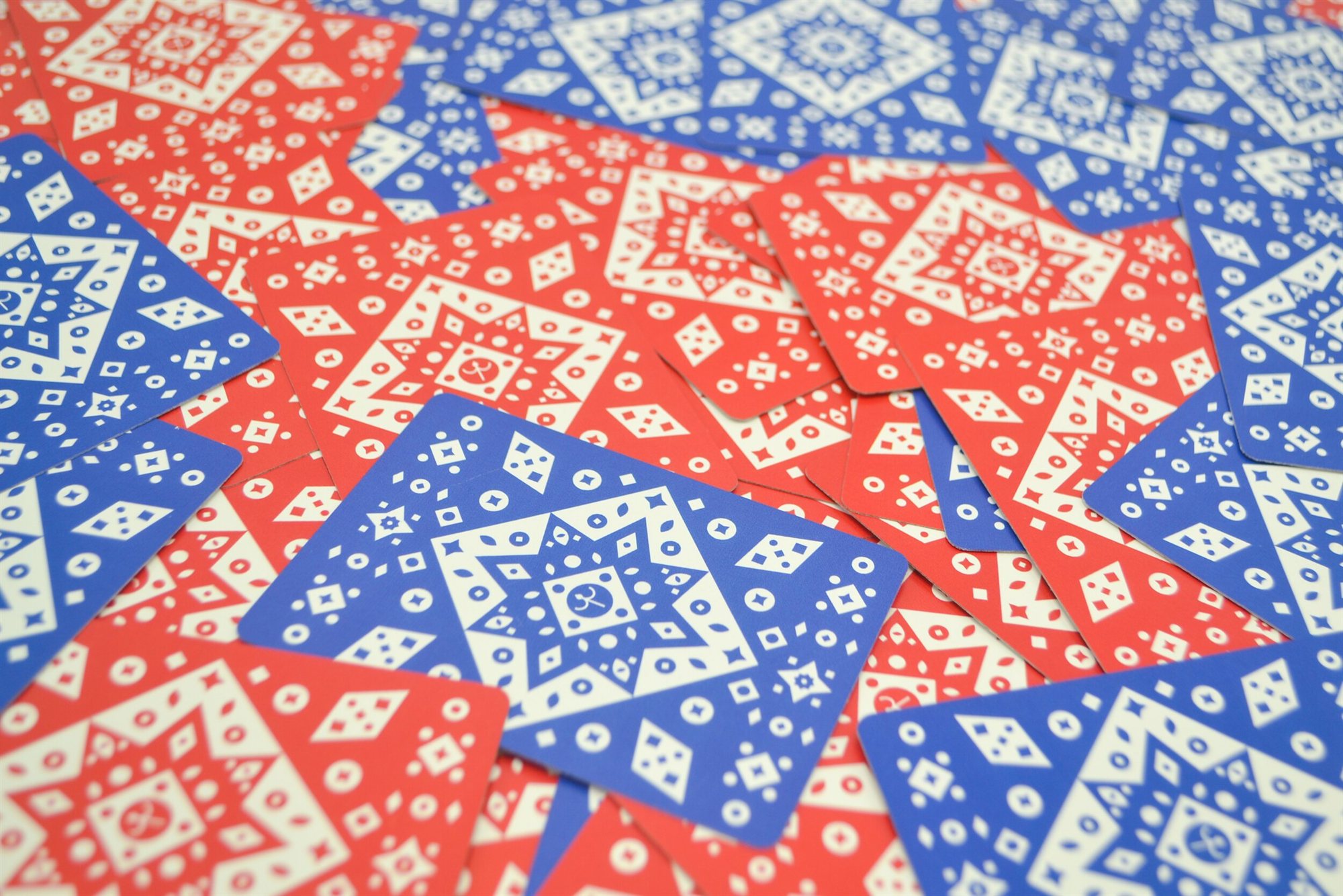 A scattered spread of red and blue patterned playing cards, representing the Carte Triestine project