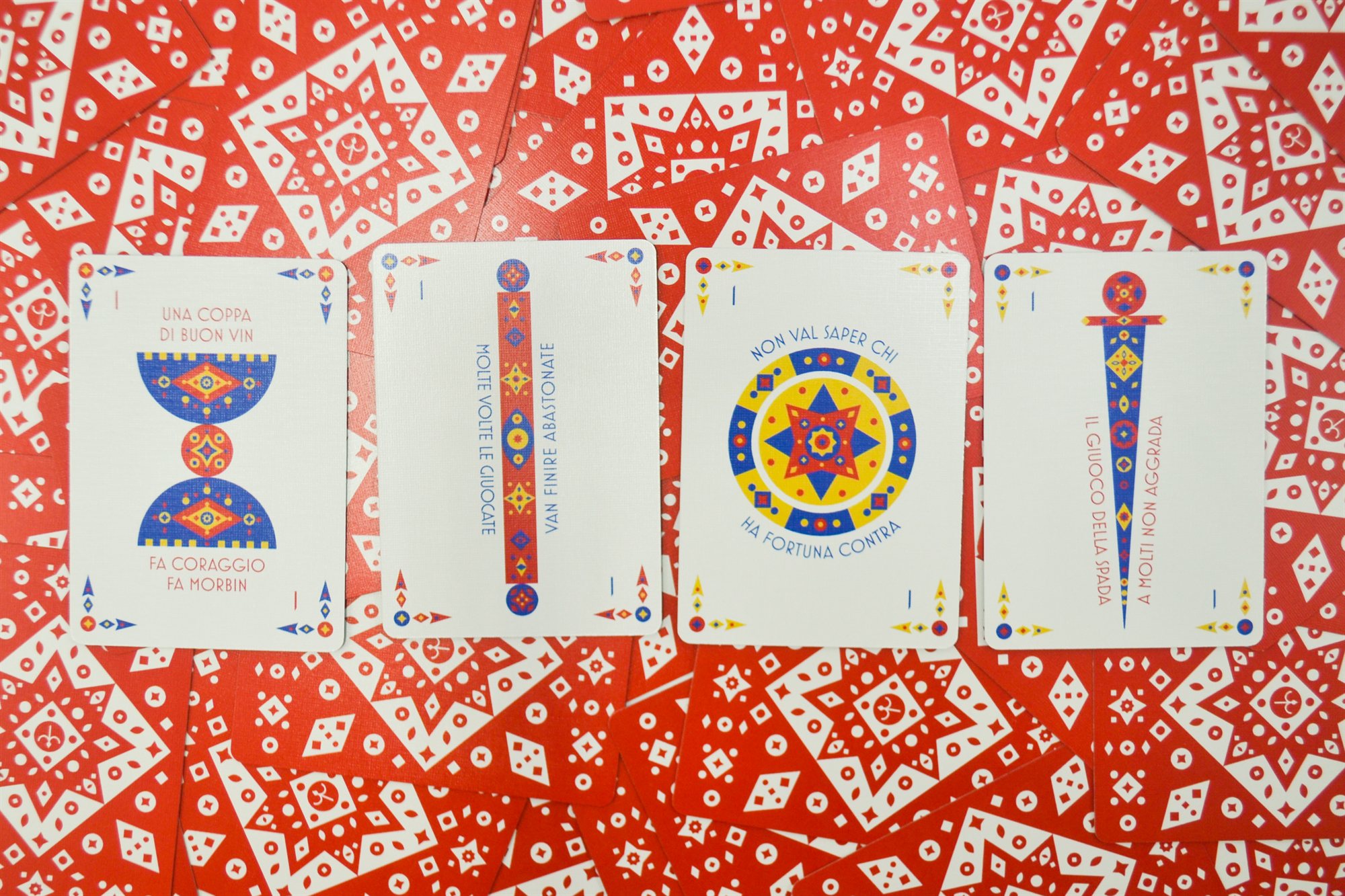 The four ace cards for cups, batons, coins, and swords laid side by side, each printed with its own Italian motto