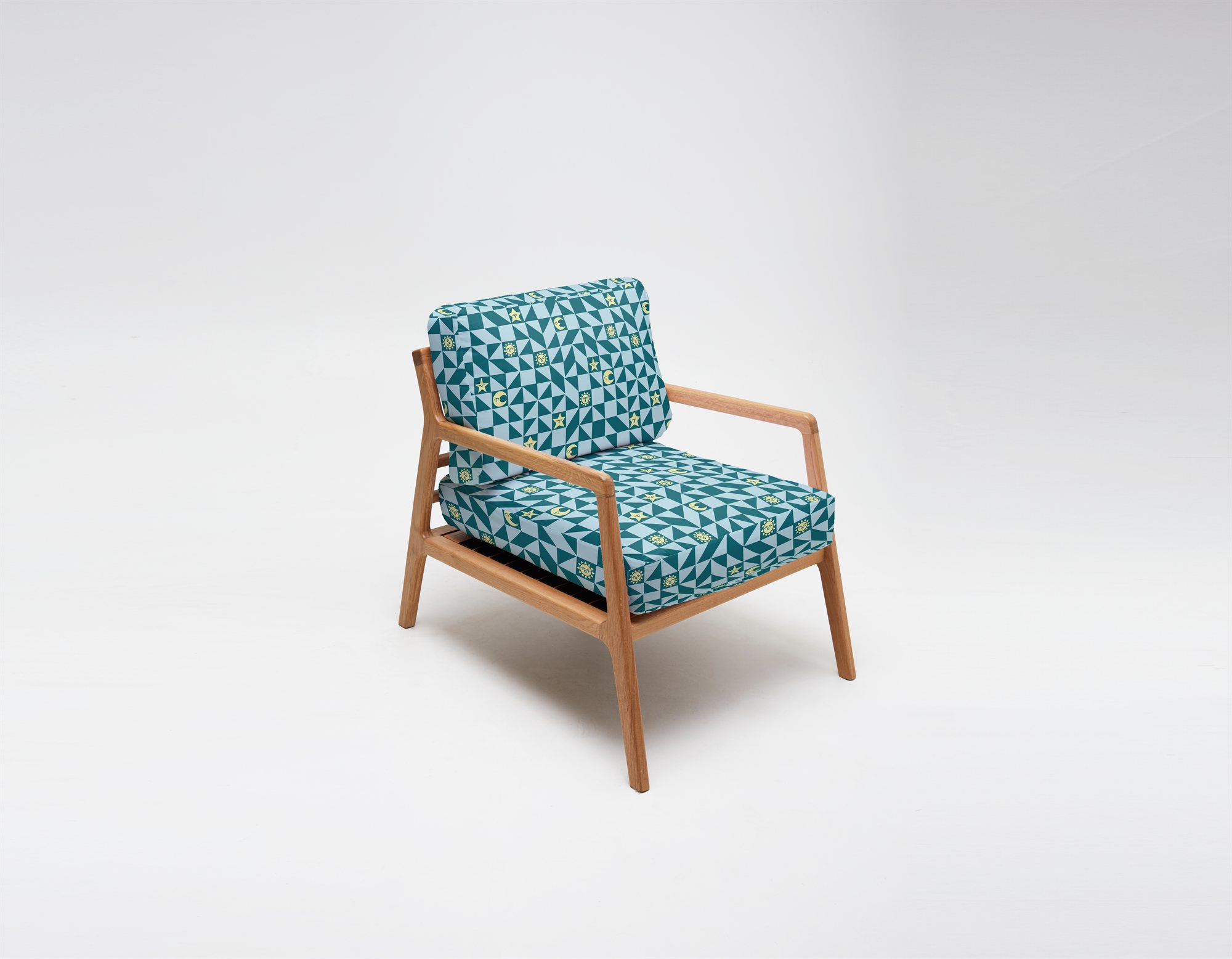 A digital mockup of a lounge chair upholstered in the teal colorway of the fabric, cushions covered in the sun, moon, and star pattern