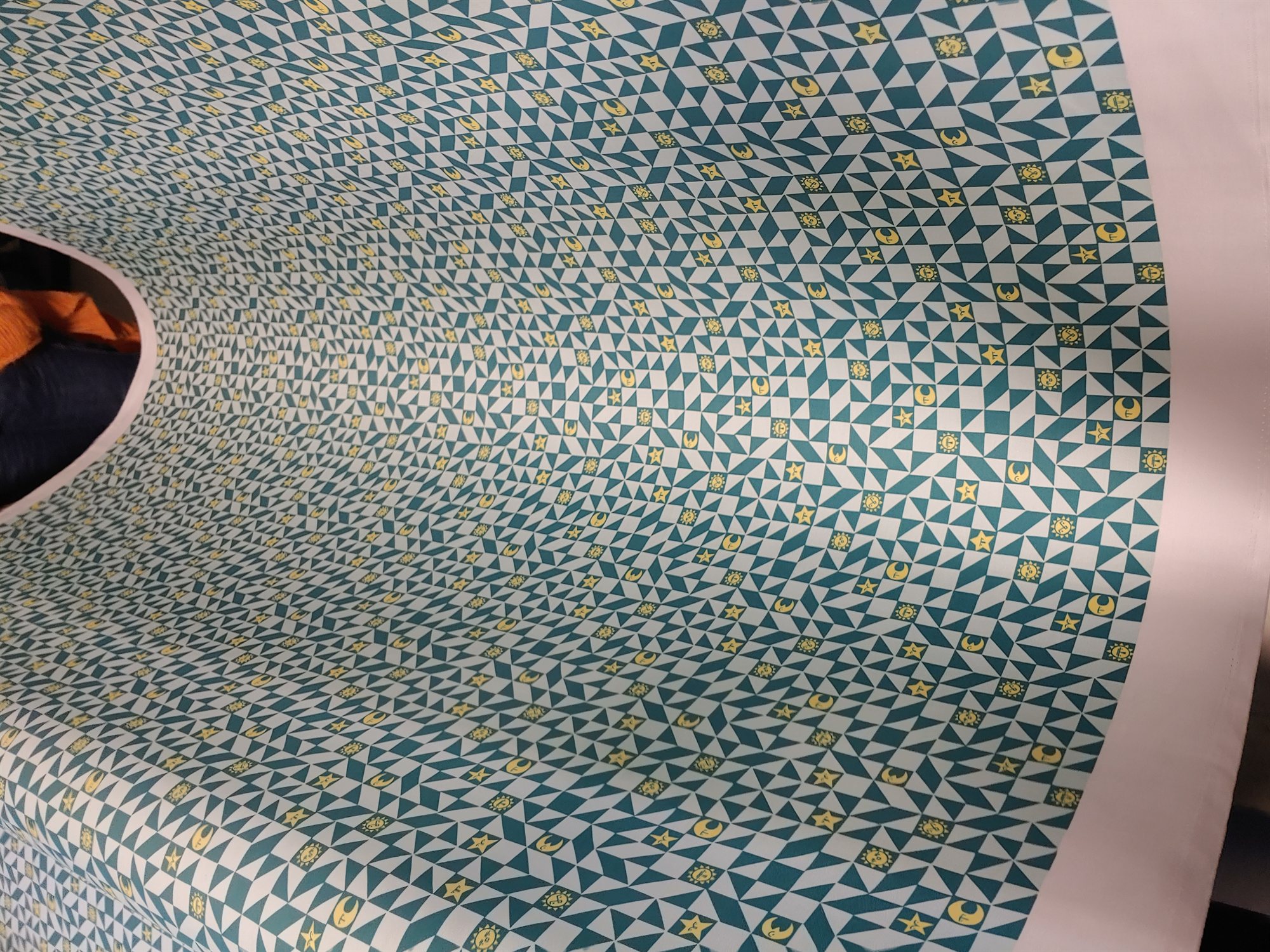 Close-up of the teal and white printed fabric draped over furniture, showing the dense repeating triangle pattern