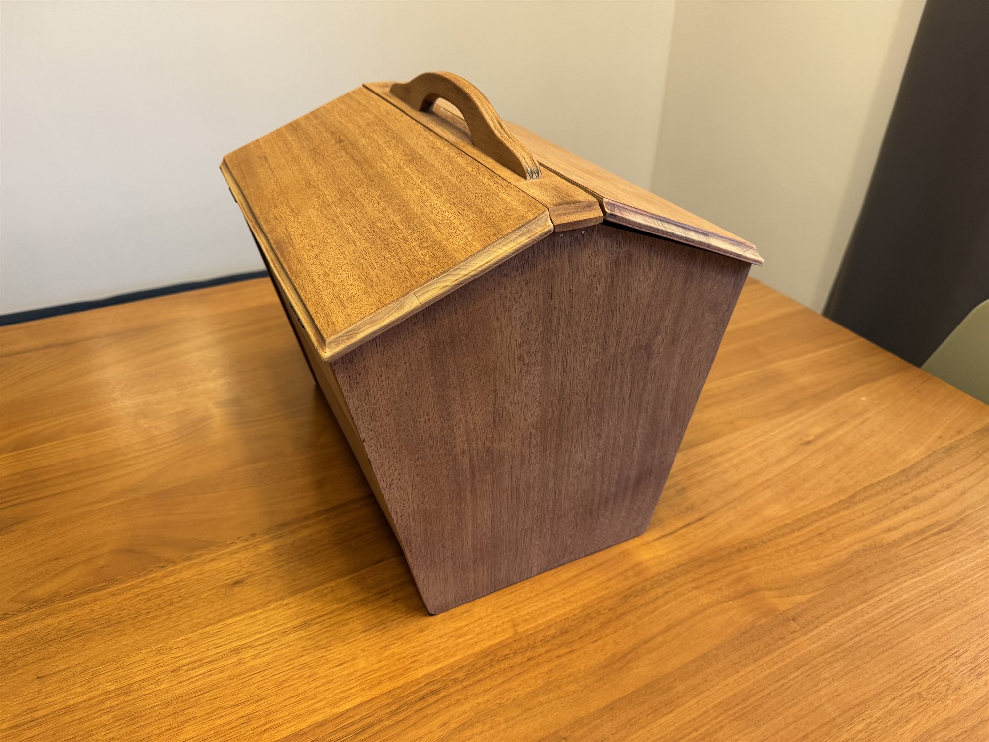 The sewing box open at an angle, its two lids spread to reveal the compartments of brass stamps and tools inside