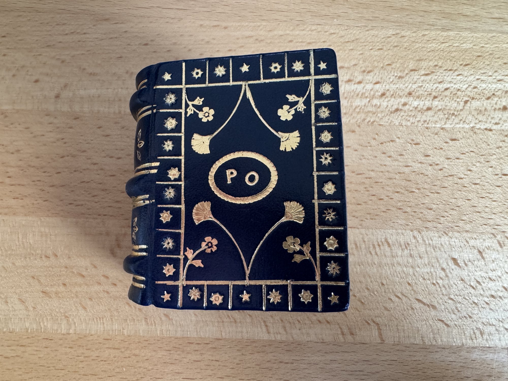 The spine of the navy leather book, showing gold-tooled floral sprays and a starred border running along the raised bands