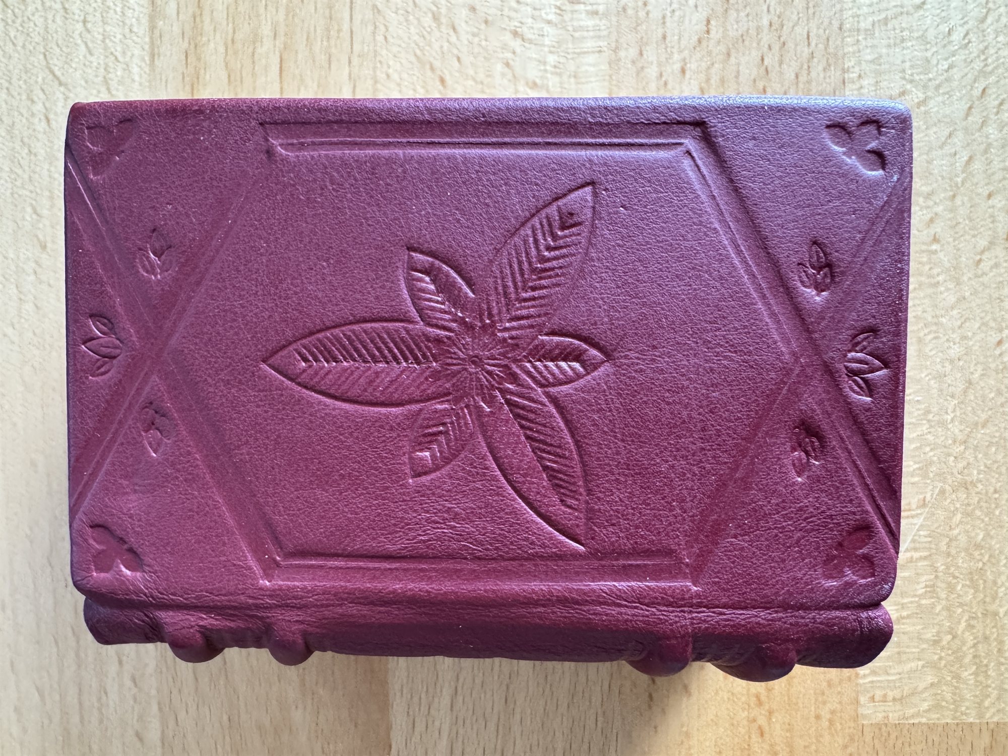 A burgundy leather book cover blind-tooled, with no gold, in a diamond lattice pattern centered on a six-petaled star flower