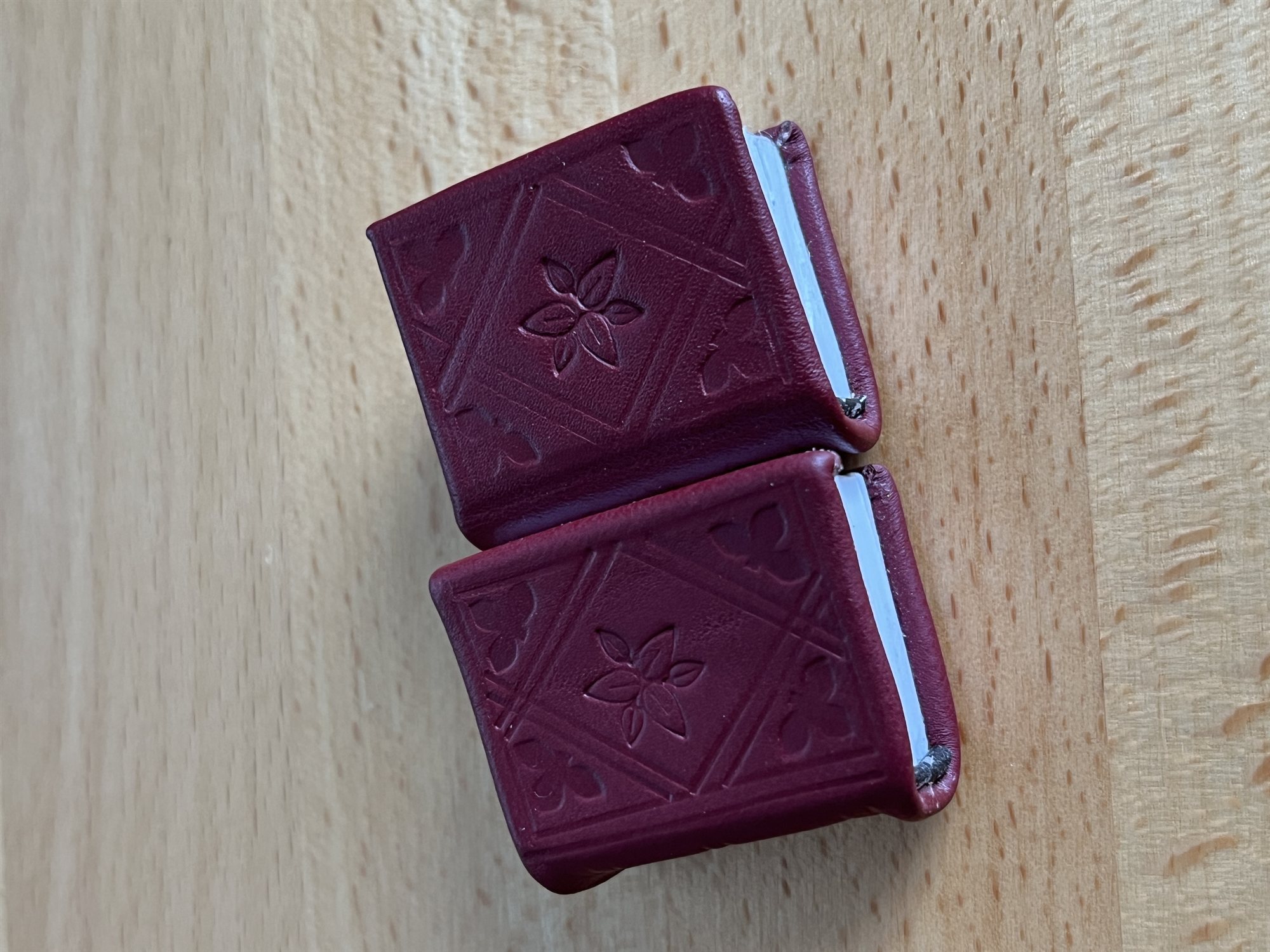 Two burgundy leather books lying spine-up, each blind-tooled with a diamond lattice and a small flower medallion