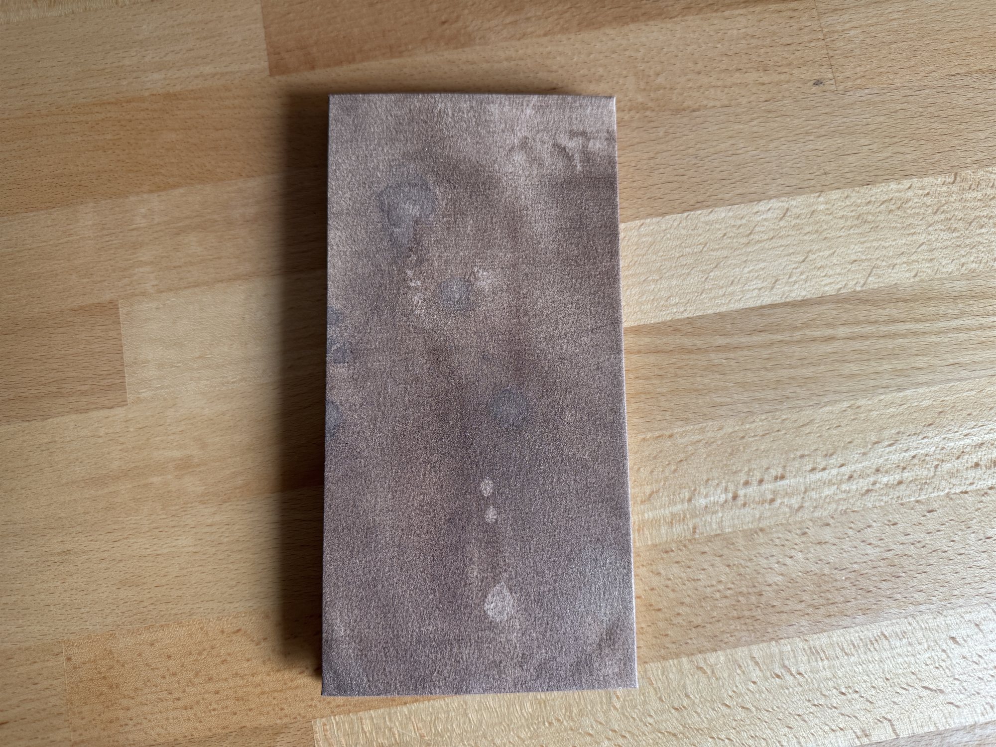 The closed codex, a mottled purple-brown decorated paper cover, resting on a wood tabletop