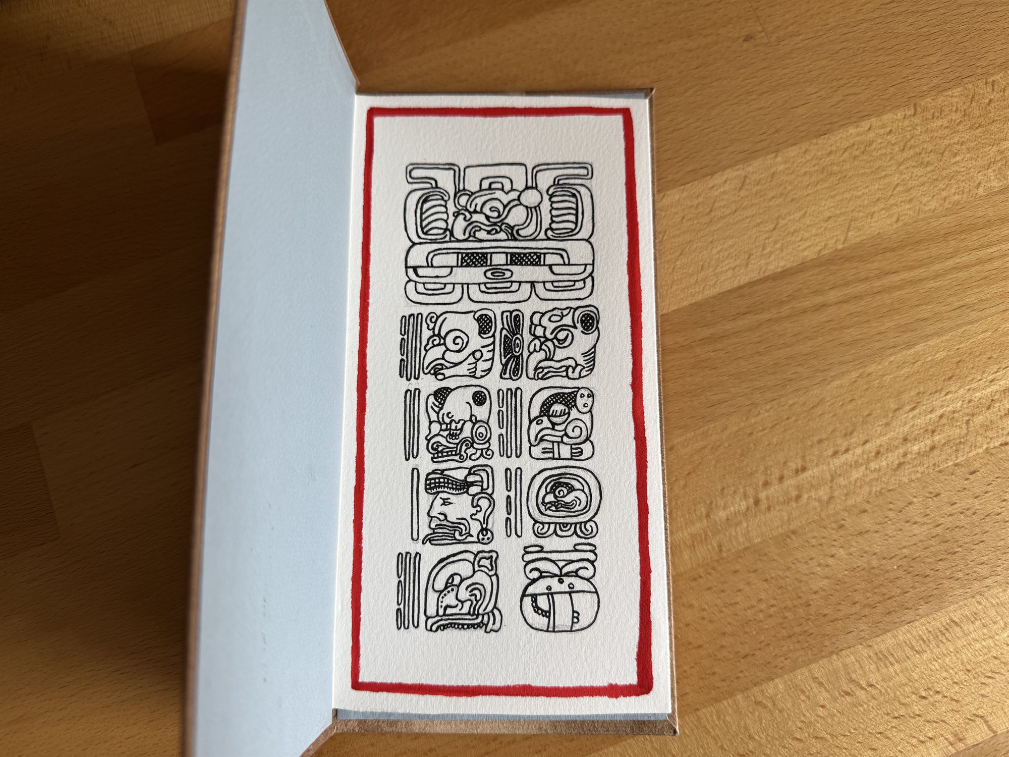 The codex opened to its first spread, a page bordered in red ink with a large glyph block at the top and four rows of paired glyphs below, each row divided by twin numeral bars