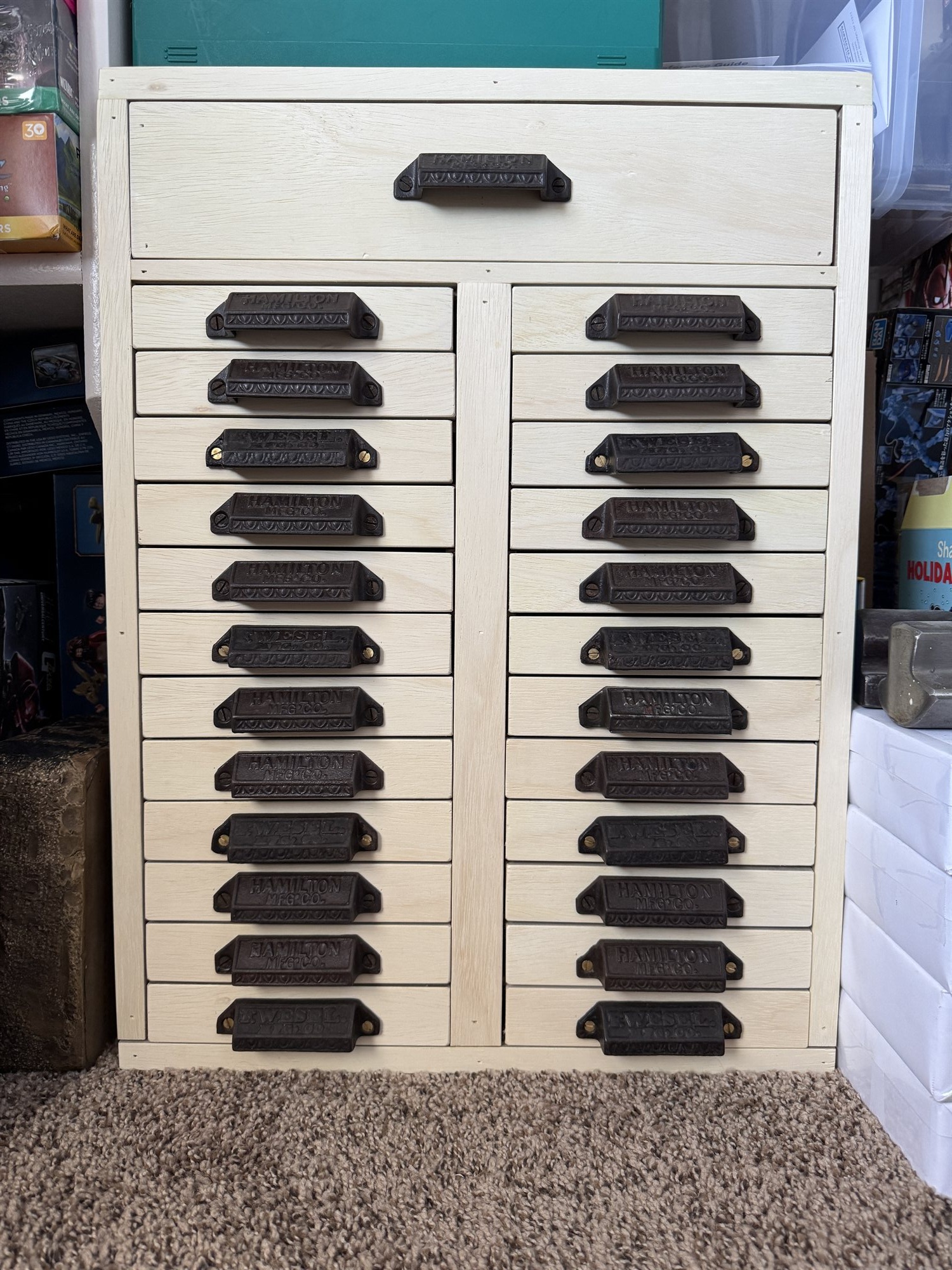 Overhead view of a cream-painted wooden cabinet with 24 case drawers fitted with dark cast iron pulls, representing the Brass Type Cabinet project