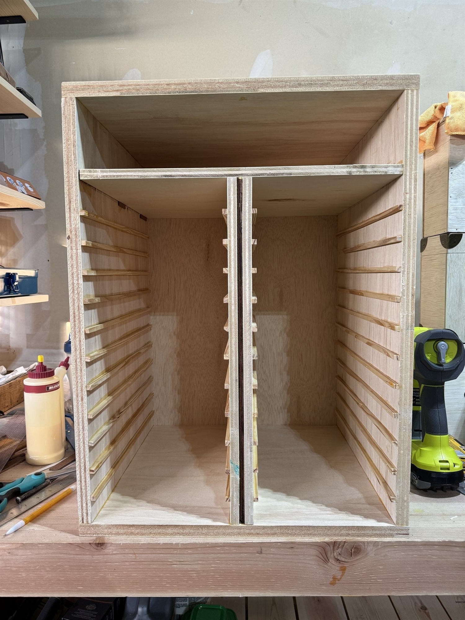 The cabinet carcass mid-build, showing the notched rails that will hold two case trays before the drawer fronts are attached