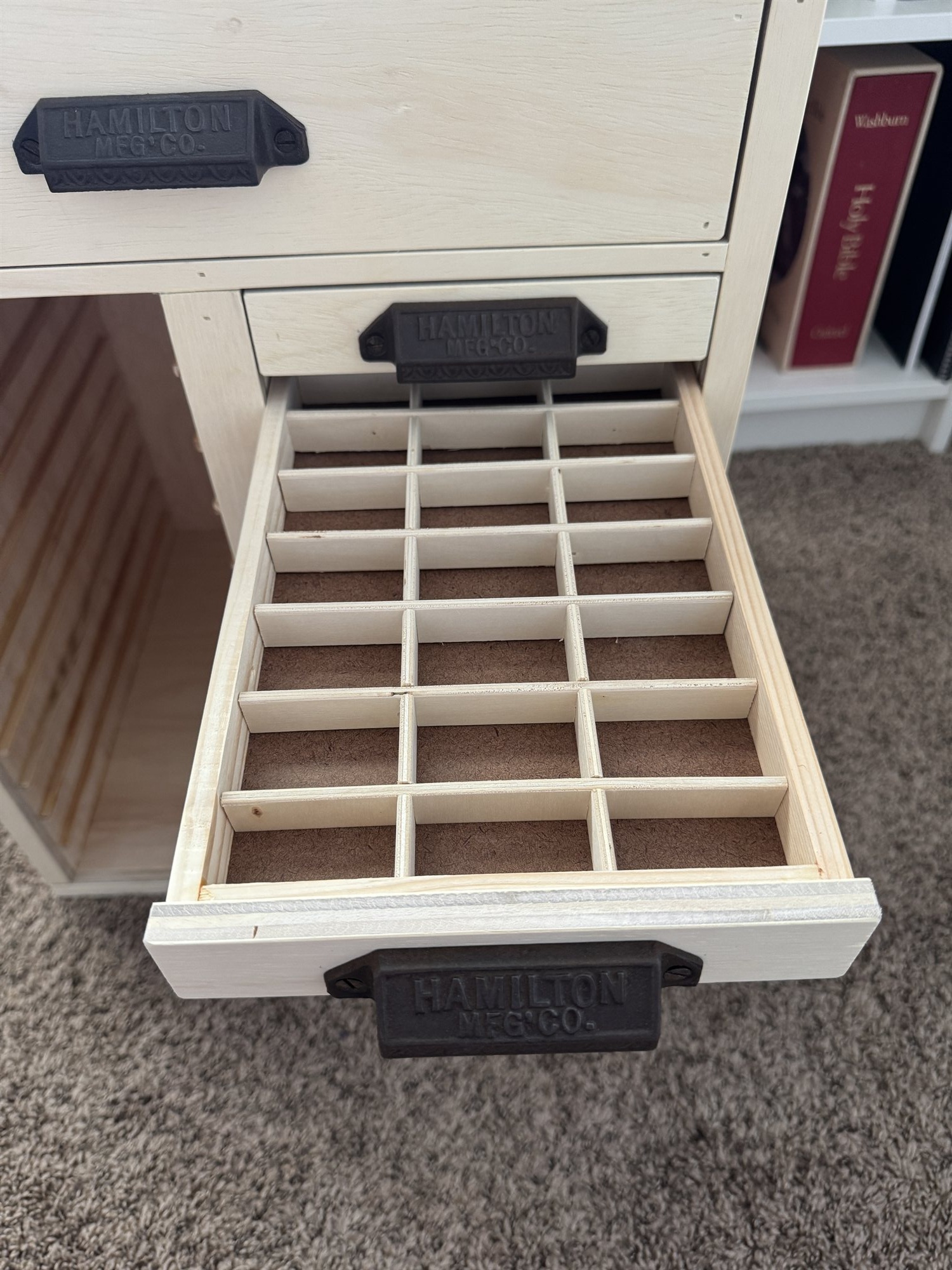 A case drawer pulled open on the finished cabinet, its thirty compartments empty and ready to be filled, flanked by the cast iron drawer pulls