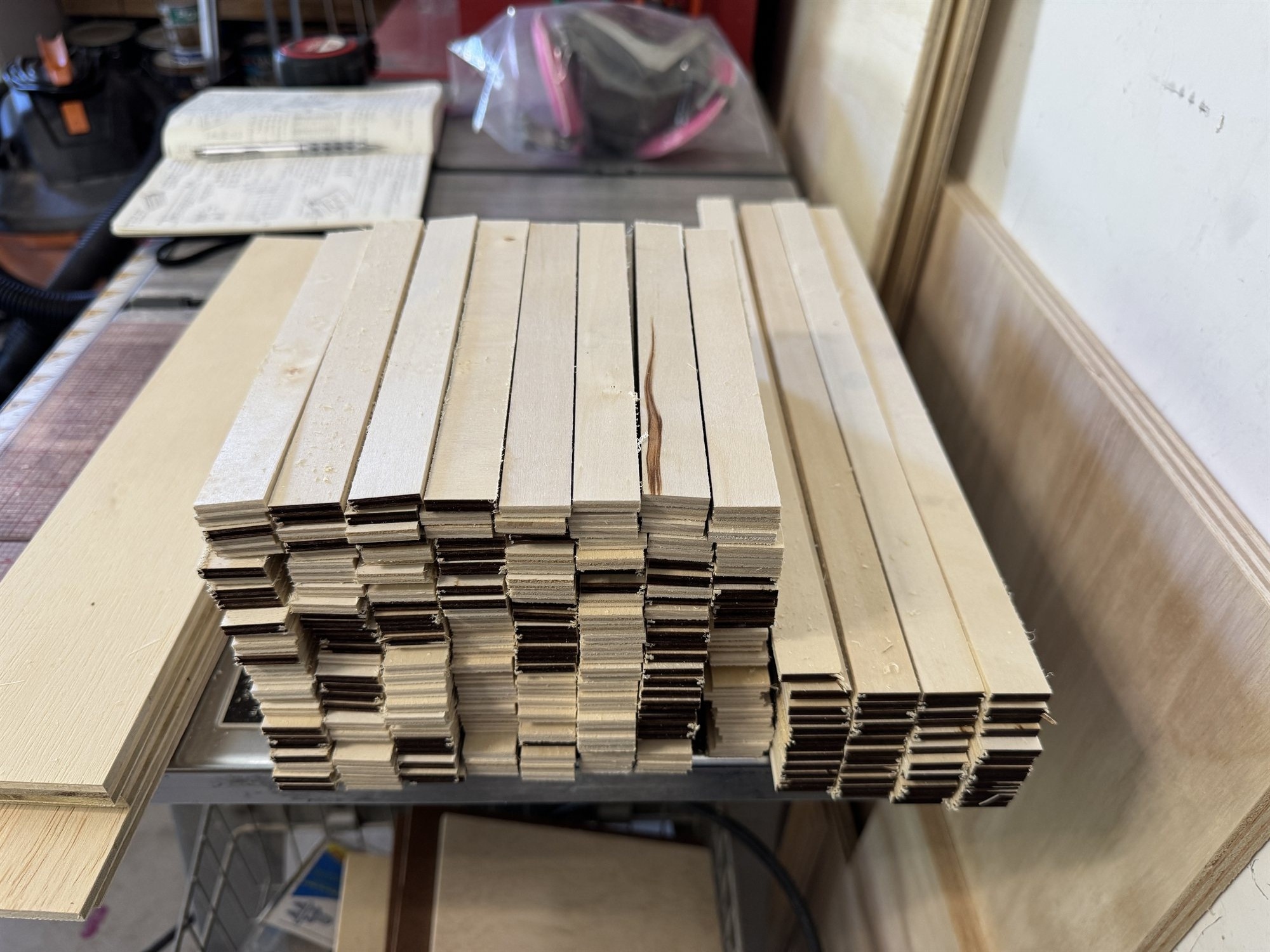 Stacks of thin plywood divider strips, freshly ripped and squared on the table saw, ready to be notched for the case grids